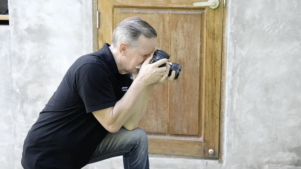 holding a DSLR camera while sitting.