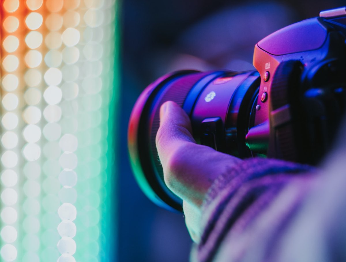close-up of camera photographing colorful neon lights.