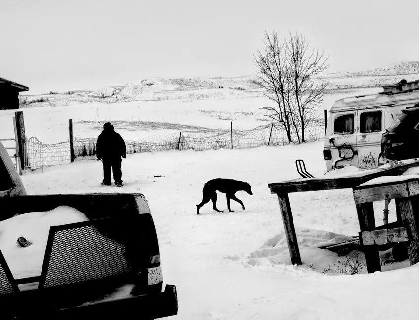 Moody black-and-white photograph of snowy back yard in inclement weather. Fine art candid photography with a with a raw, unfiltered tone.