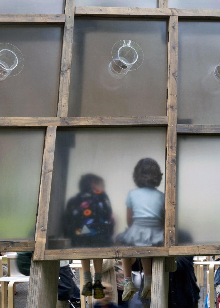 An image of two people sitting behind the glass window of a structure by Duccio Malagamba.
