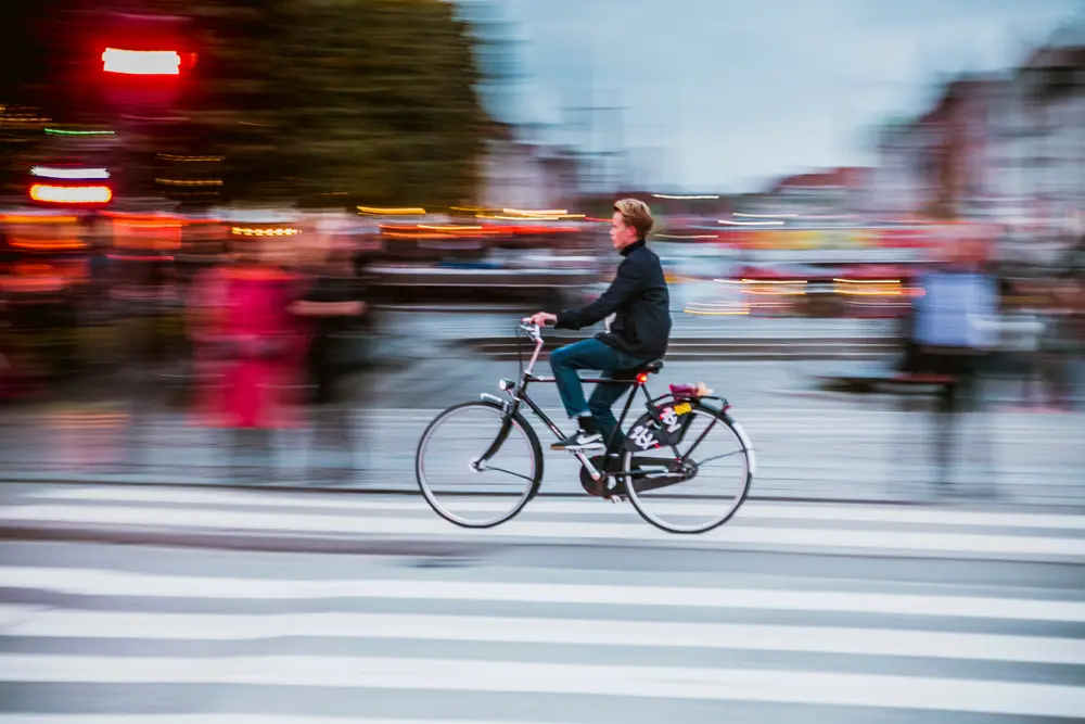 Cyclist driving down urban street. Motion blur in background, tracked shot.