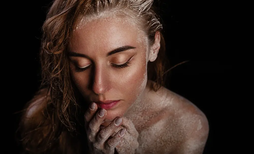 Fine art portrait of young woman seated in a pensive mood, closed eyes. Low-key lighting with dark background.