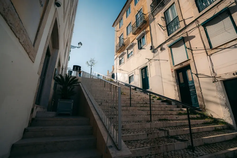Streetside view in Old Lisbon, Portugal. Low-level shot facing up large staircase with historical buildings.