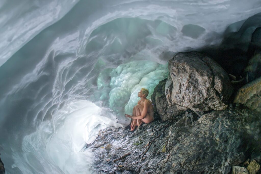 An image of a woman curled up against some rocks against what looks like a raging current of water by Laura Zalenga.