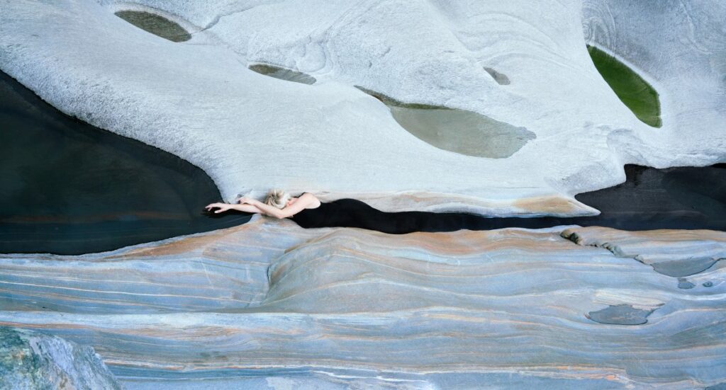 An image of a woman lying between two rock flats seemingly blending into the water between by Laura Zalenga.