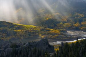 A landscape photography drone image of sun rays lighting up an mountainous region.