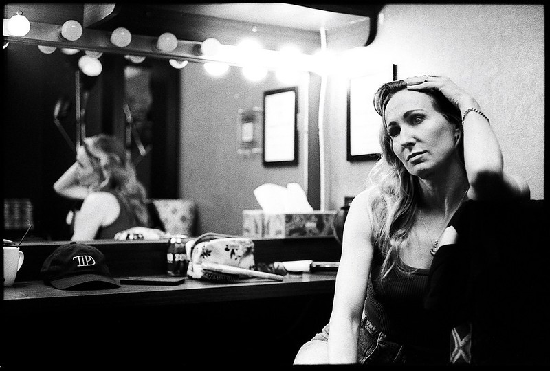 A black and white image of a woman sitting in front of a mirror photographed by Johnny Martyr.