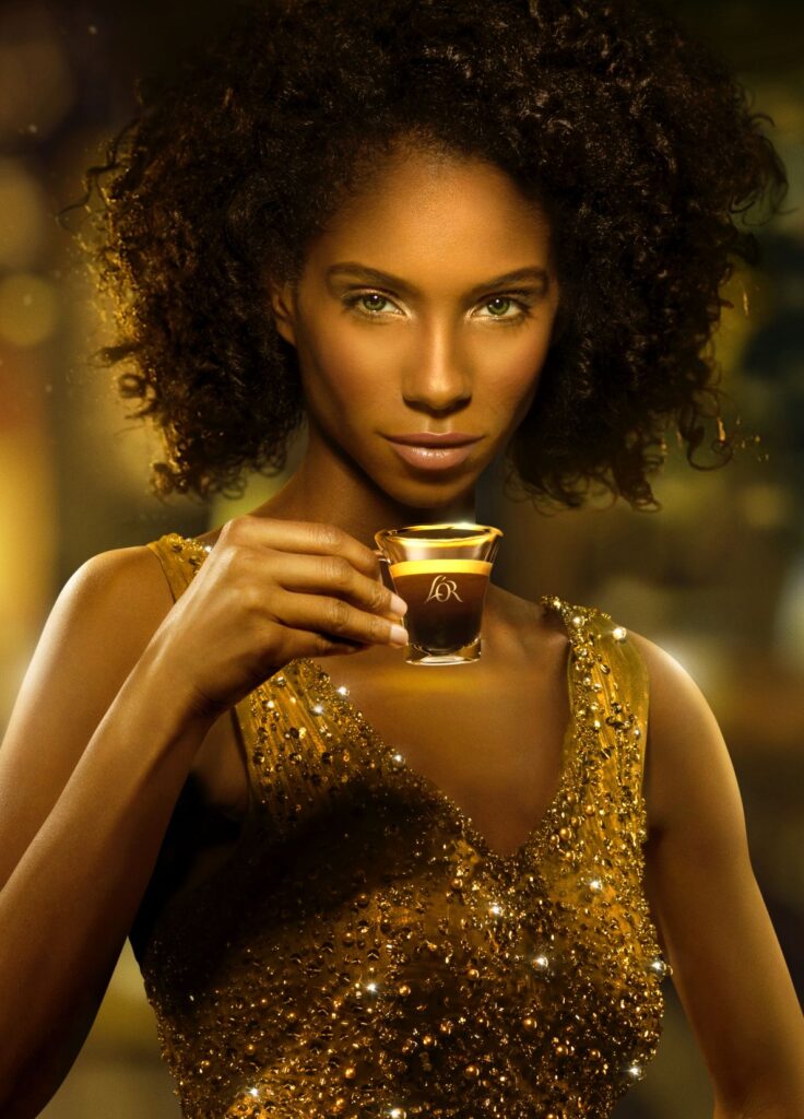 An image of a model holding a small cup of what looks like espresso by Jonathan Knowles.