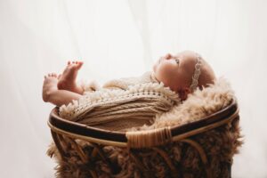 A side photo of a newborn in a basket by Kristeen Waddell.