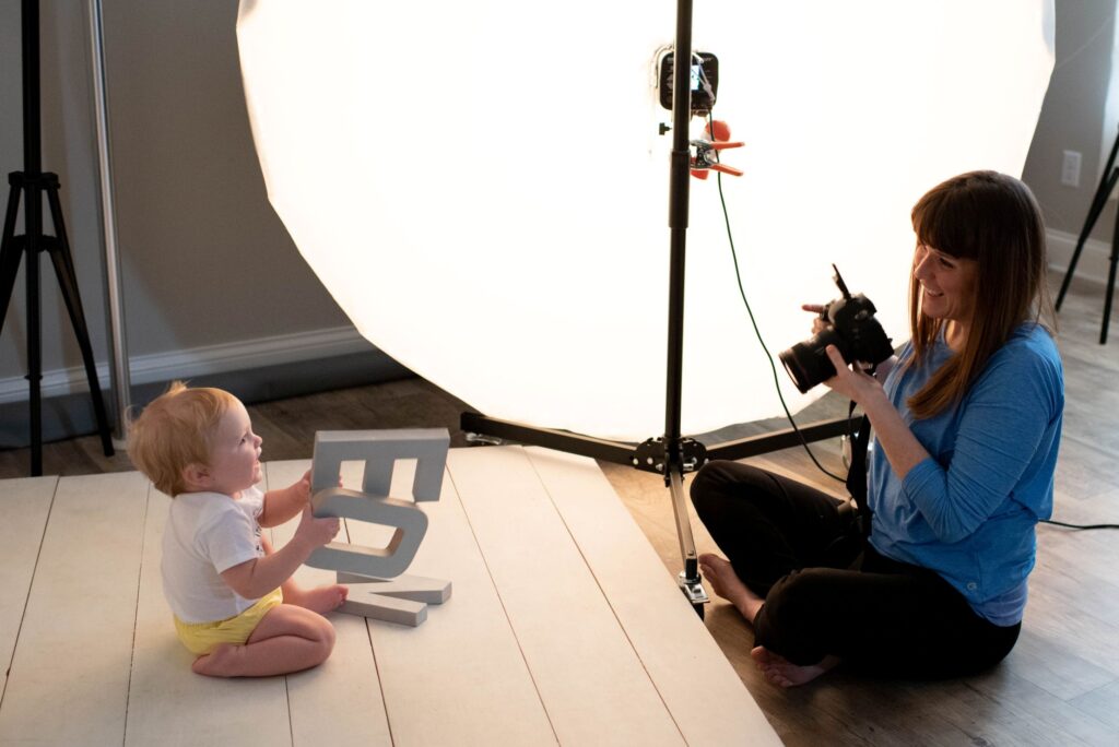 An image of Kristeen Waddell working with a toddler on set to get a photograph.
