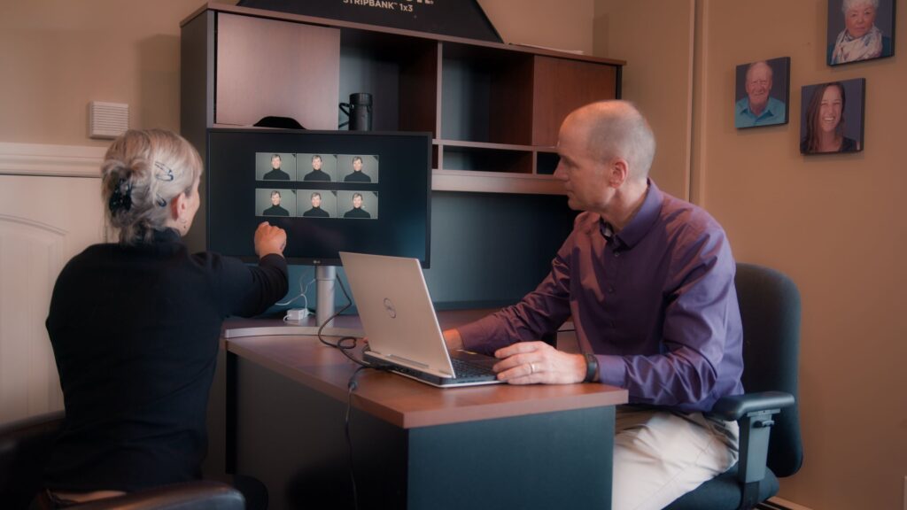 An image of Peter Istvan at his desk showing a client some photos he shot.