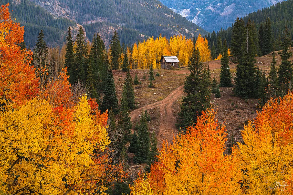 Small mountain cabin surrounded by colorful fall aspens in the San Juan Mountains.