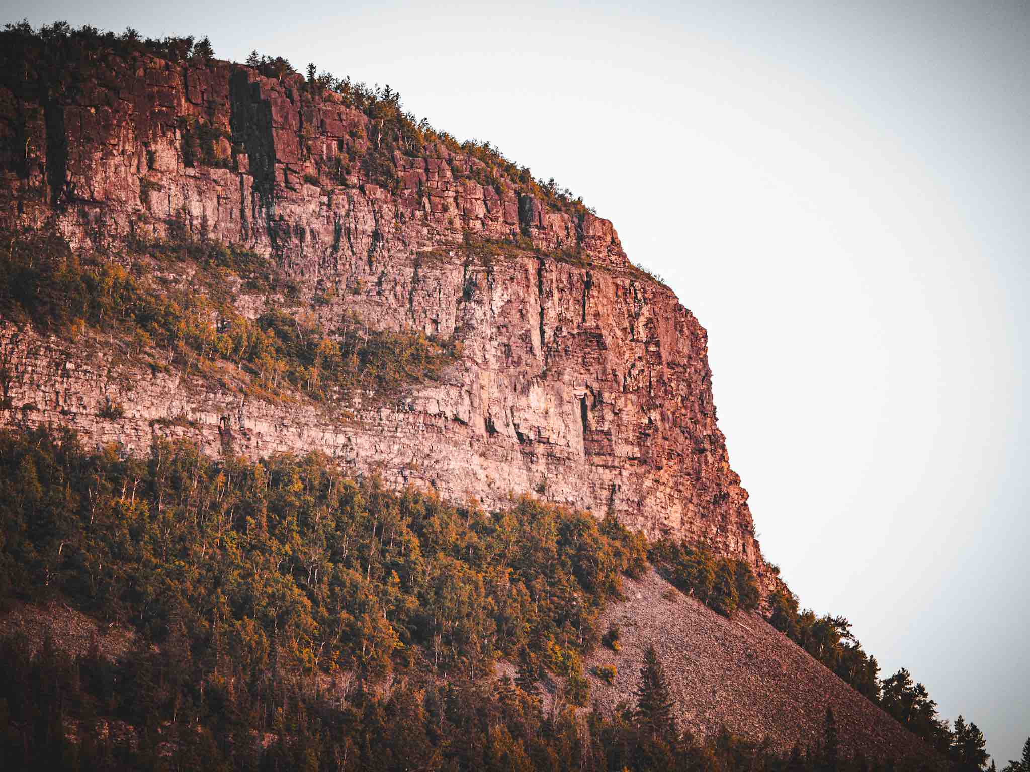 Cliff face lit by directional sunlight with deep shadows.