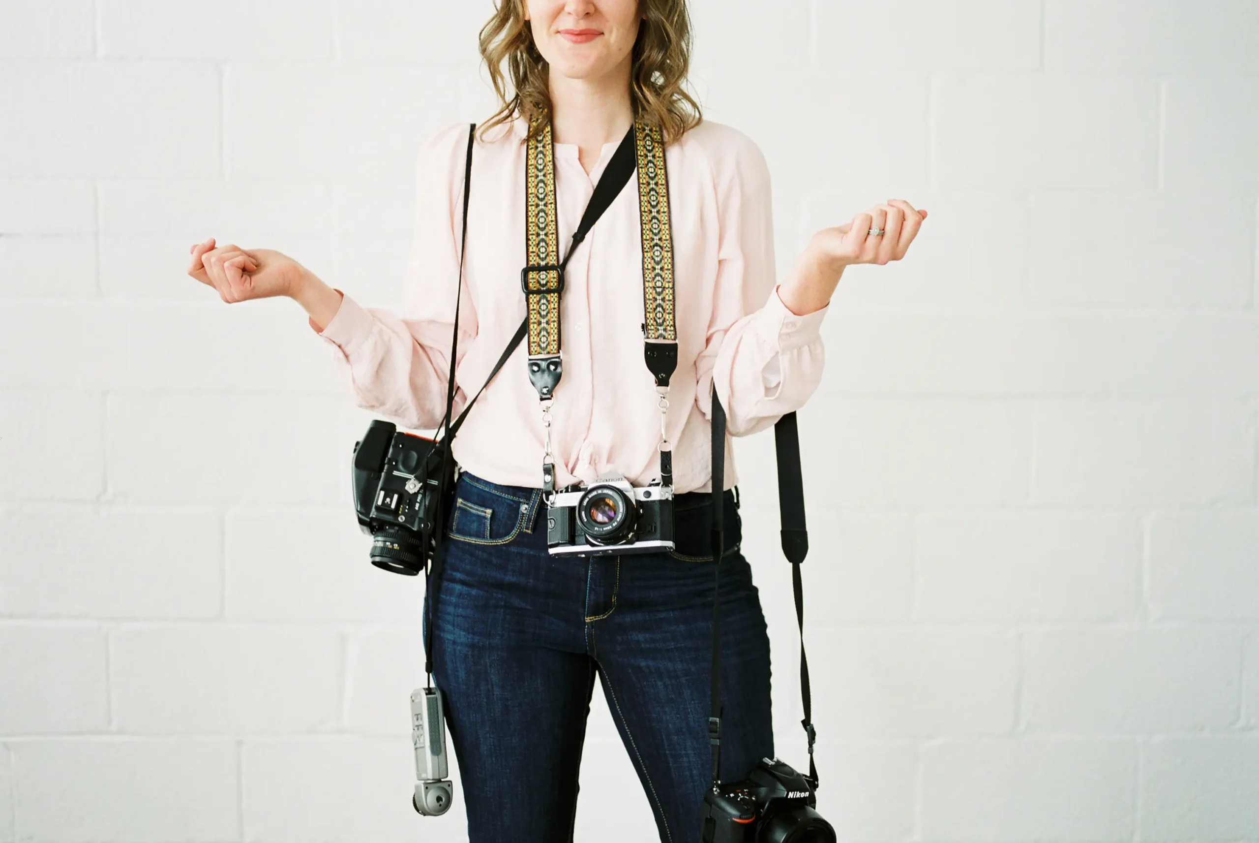 Photographer wearing multiple cameras and lenses, illustrating a working food photography gear setup with primary and backup bodies.