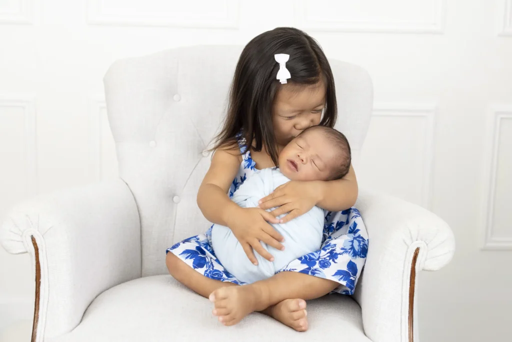 An image of a younger sister embracing her newborn sibling by Brittany DeMaio.