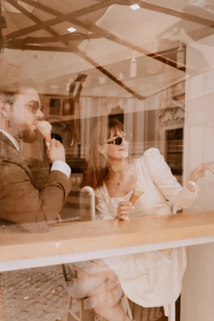 An image of a couple having ice cream from behind a window by Lucrezia Bastoni.
