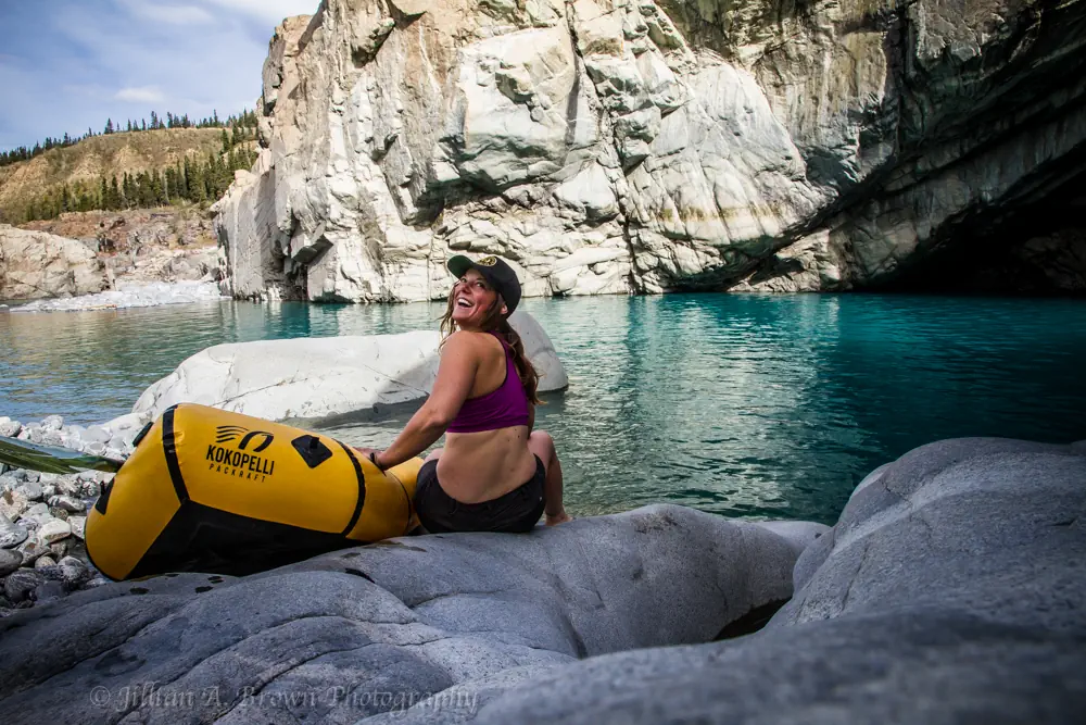 An image of Jillian Brown sitting by her kayak near a lake.