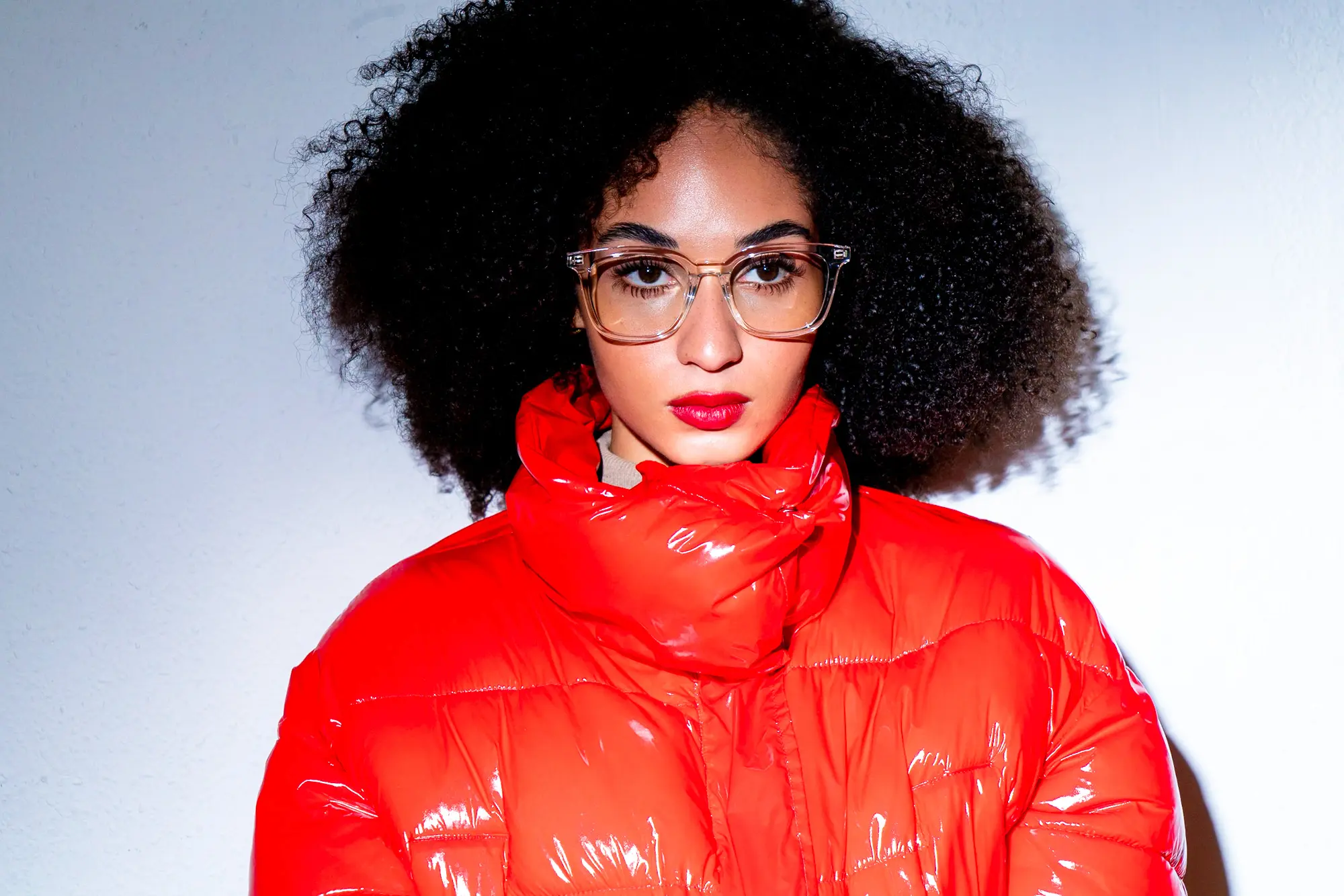 Model in red puffer jacket, direct gaze.