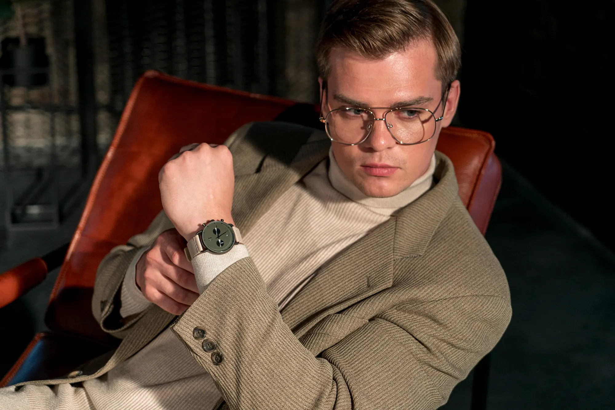 Male model seated, controlled posture.