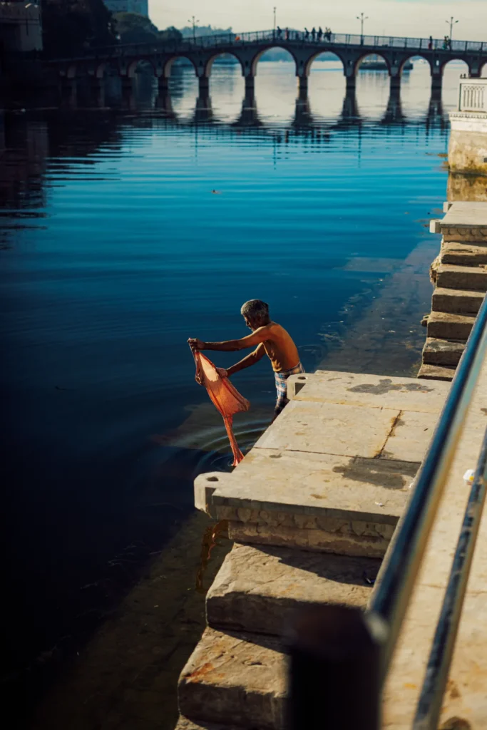 A photograph of a man in India washing clothes in a river by Paulie Marechal.
