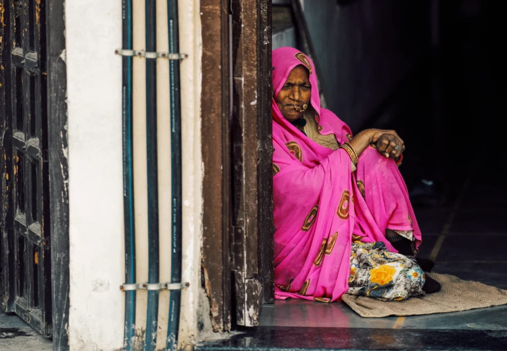A image of a woman in India sitting against a wall by Paulie Marechal.