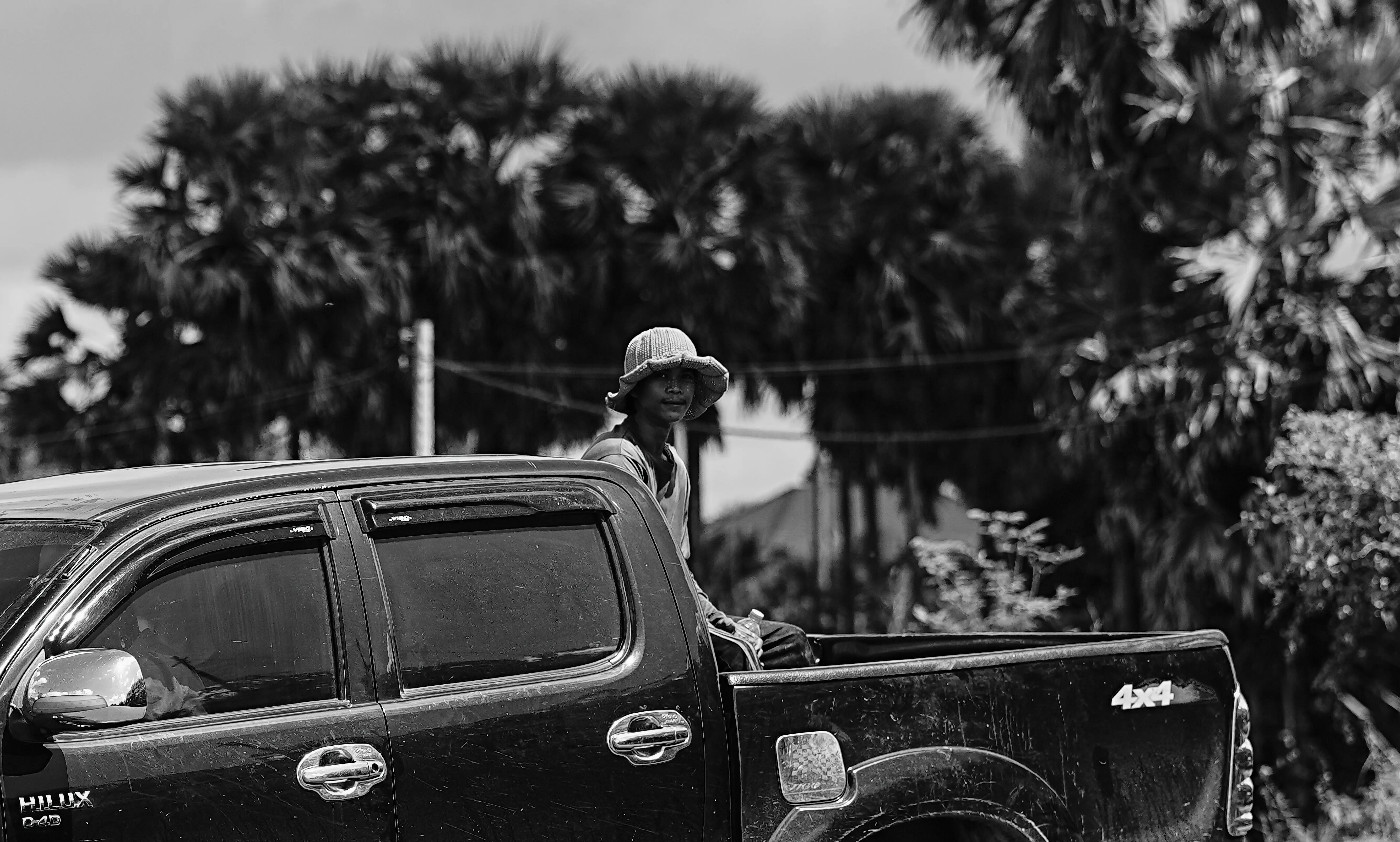 Farmer sitting in the back of a pickup truck along a rural road near Siem Reap, Cambodia.