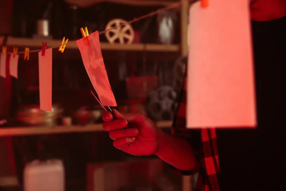 A close-up of a person taking photos off the photo drying line.