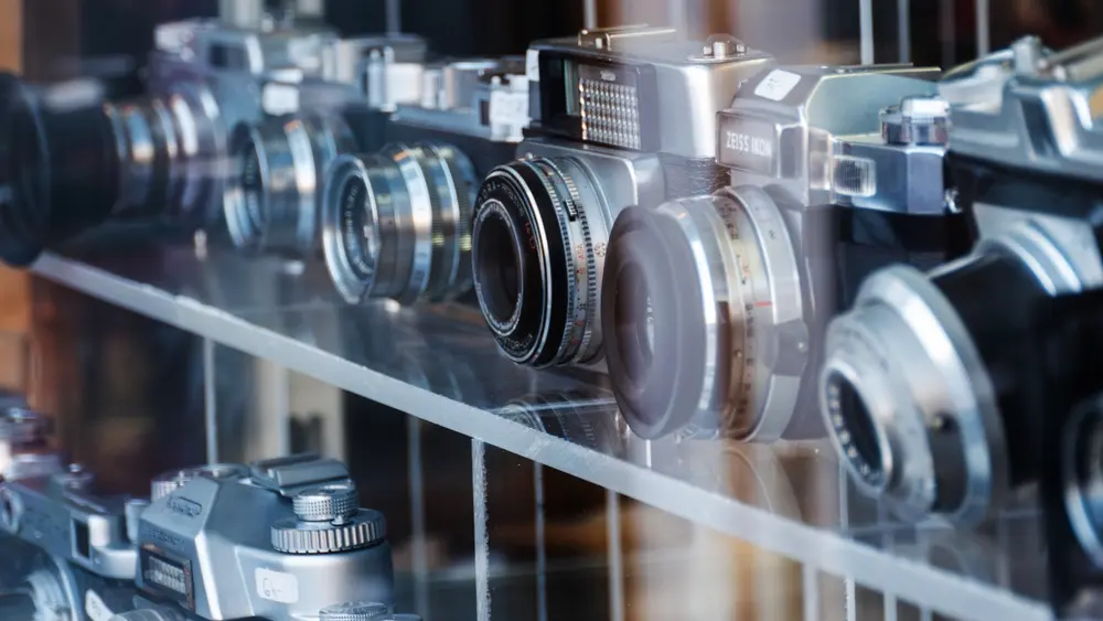 Collection of vintage film cameras displayed on a glass shelf in a camera shop.
