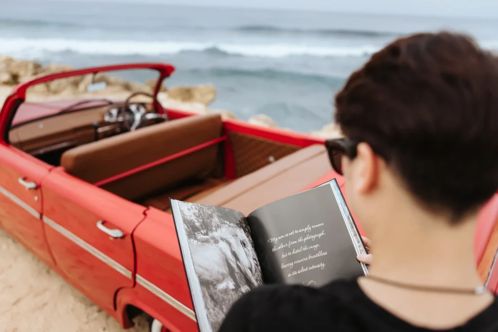 An over-the-shoulder view of Ian's book "The Silent Savannah" as he stands by a car and shoreline.