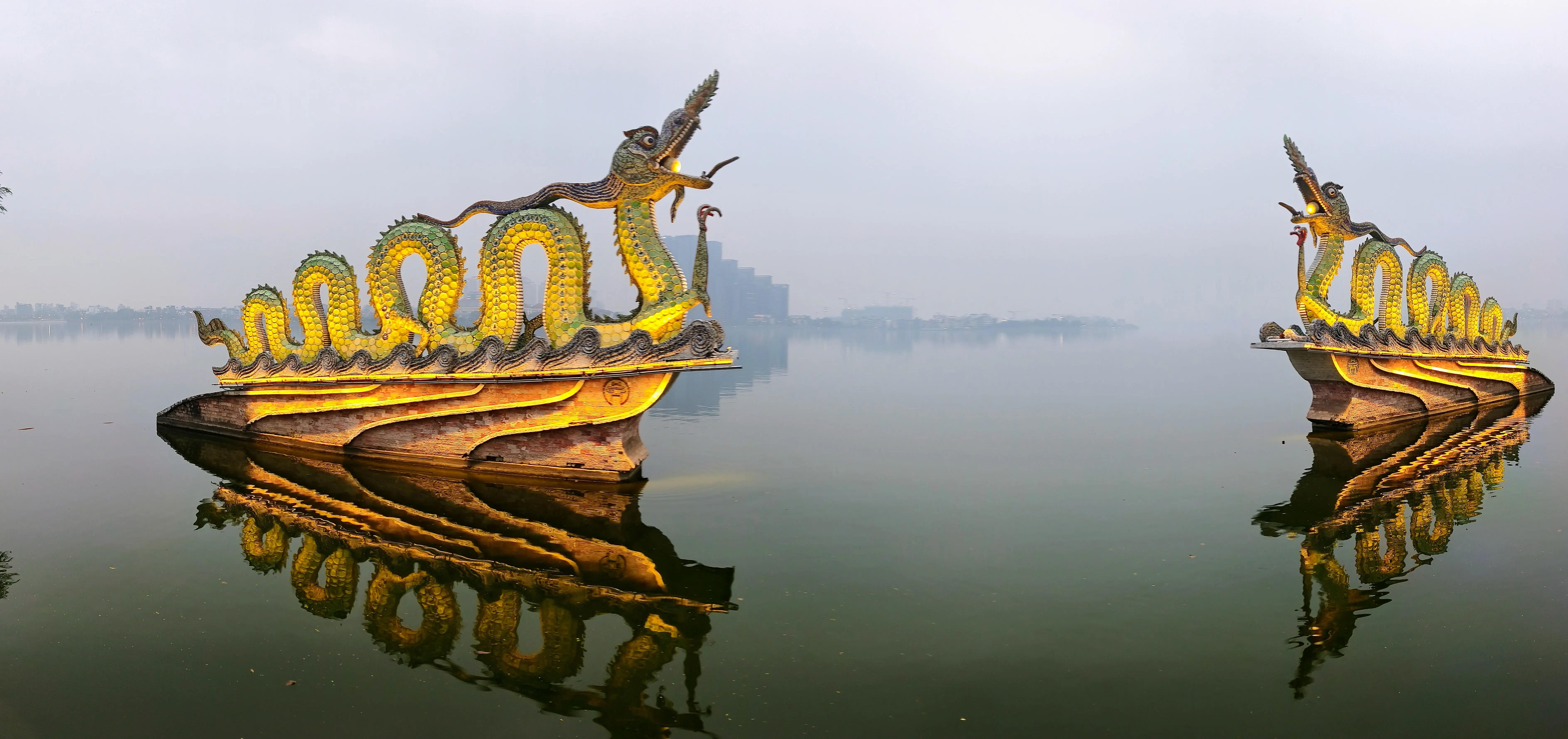 Two golden dragon statues reflected in the still waters of West Lake, Hanoi on a misty morning. A visually arresting scene that draws most photographers to the obvious subject and symmetry.