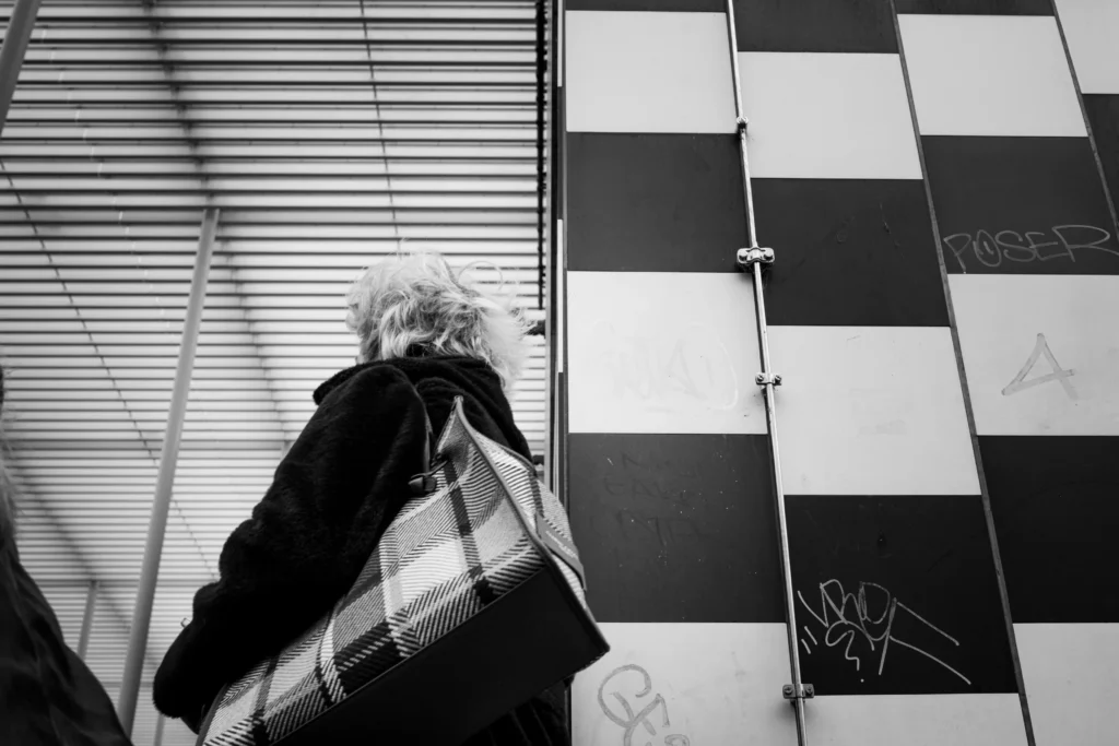 A black and white photo of someone holding a flannel bag in front of some construction by Frederic Paulussen.