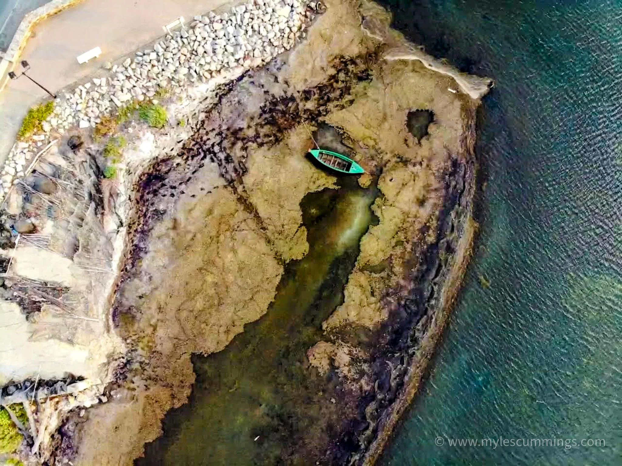 Aerial view of a rocky turquoise coastline with a winding path