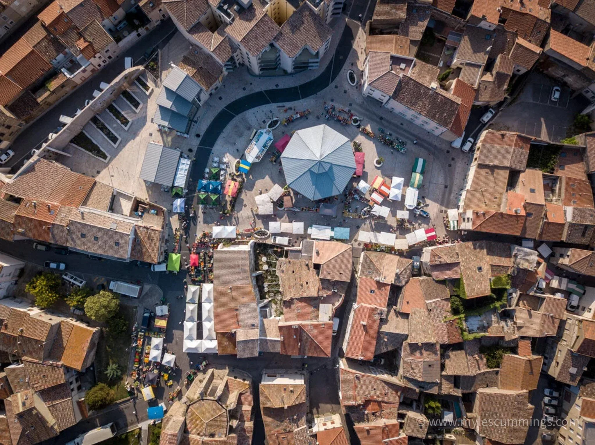 Top-down aerial view of a historic town's terracotta rooftops and circular plaza