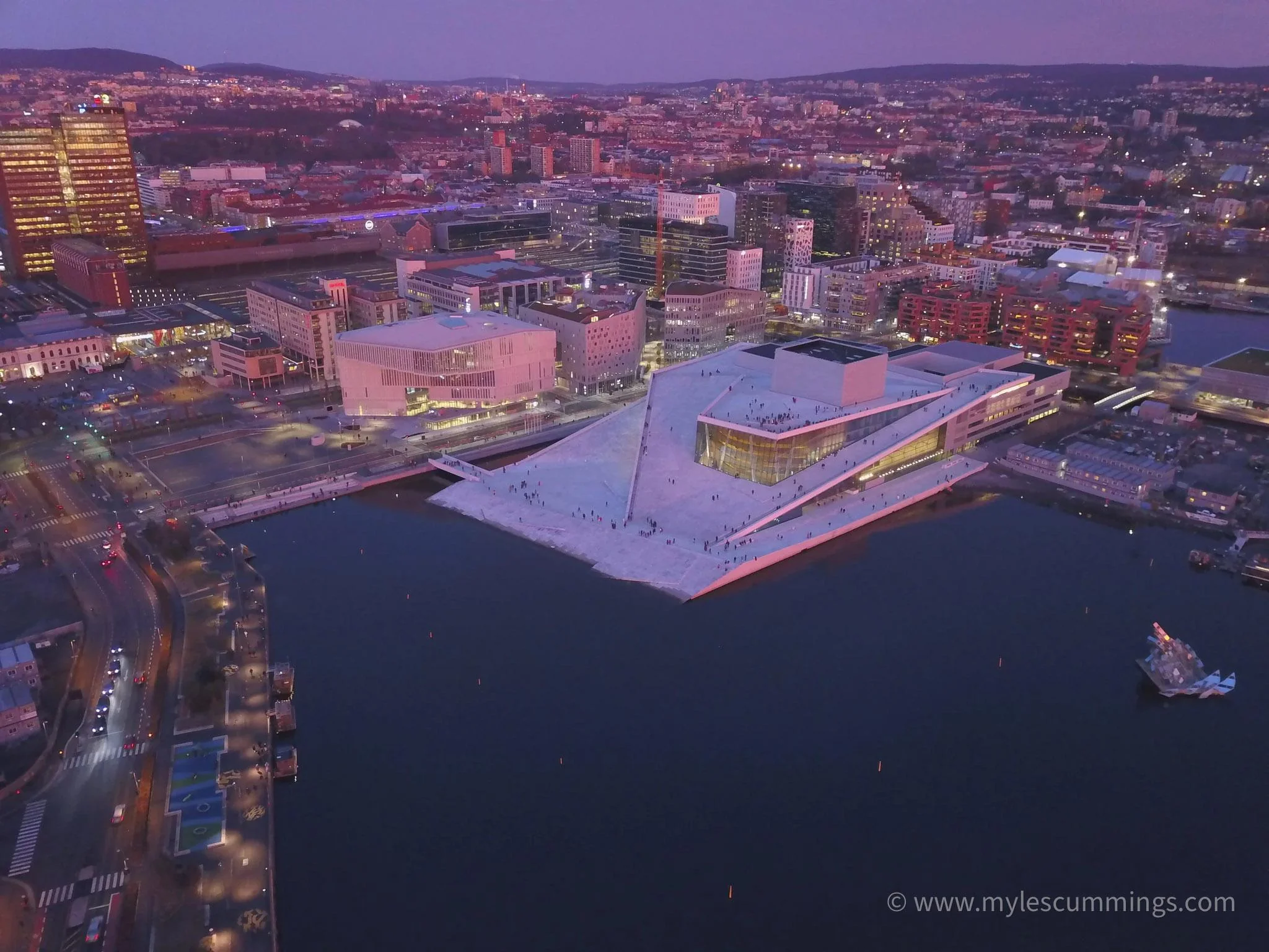 Aerial dusk view of a waterfront marina with an illuminated building