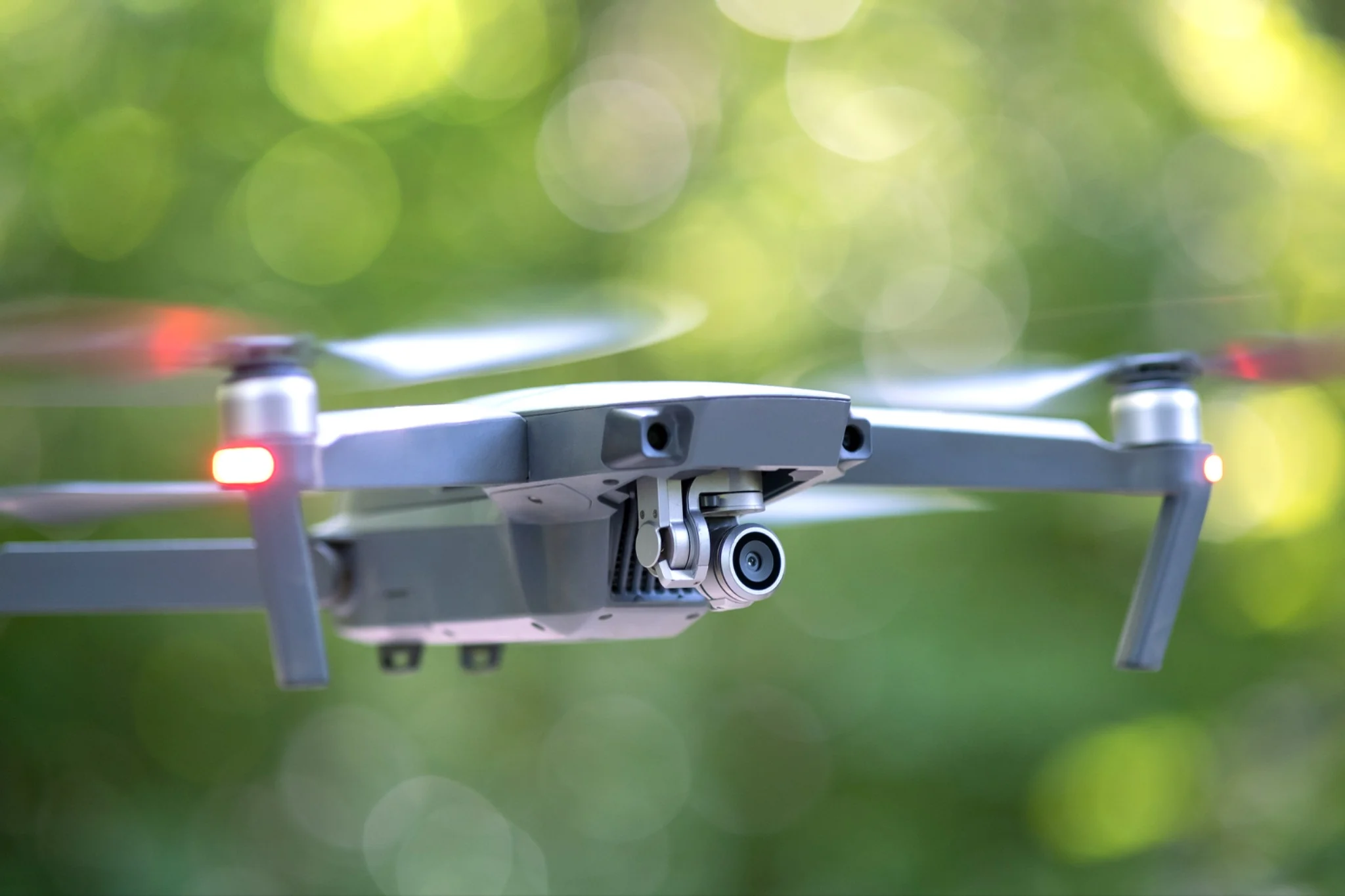 A dark quadcopter drone hovering in mid-air against a green background