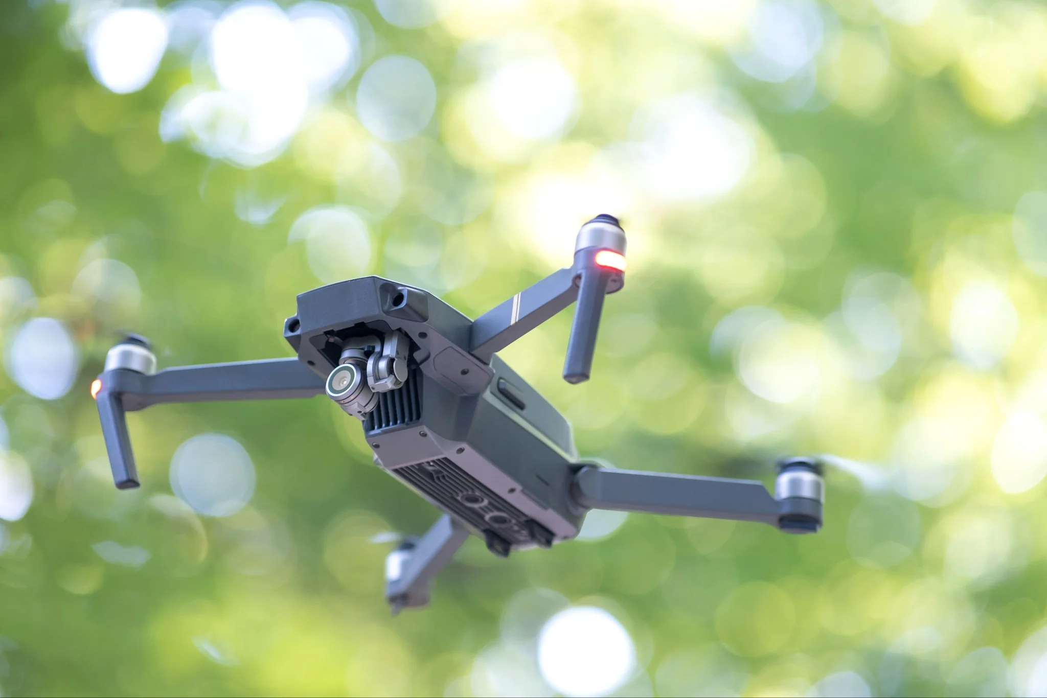 A DJI Mavic-style drone hovering steadily above a grassy field