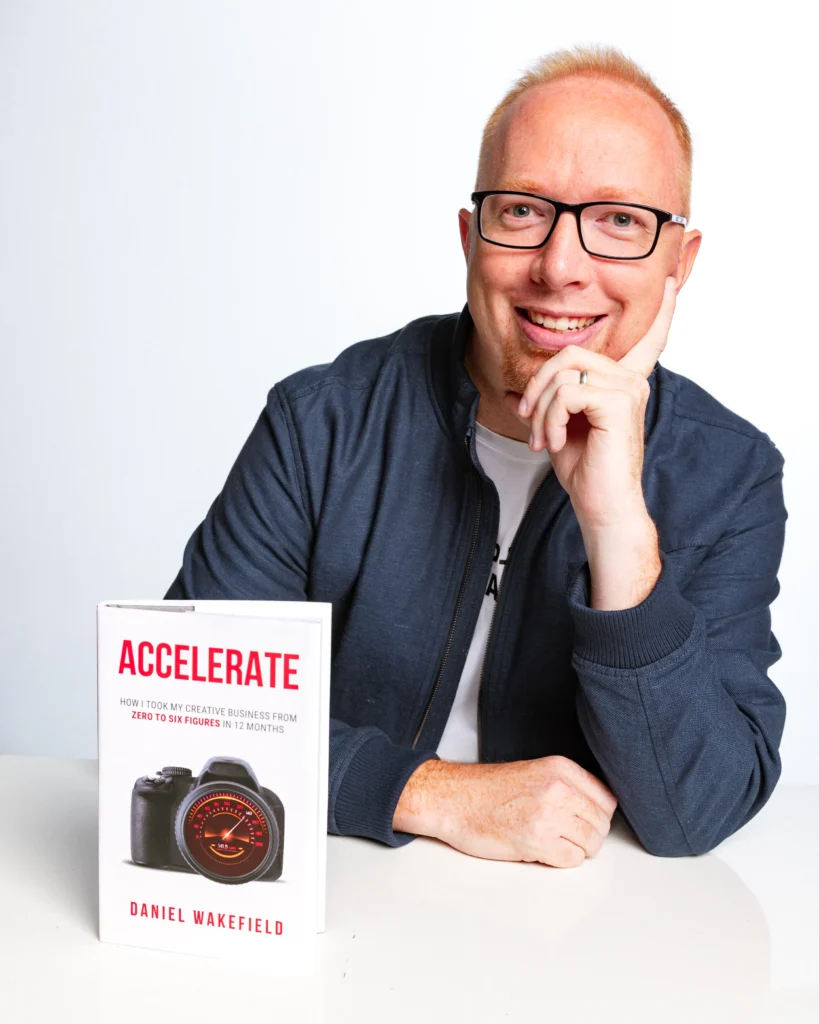 A headshot of photographer Daniel Wakefield with his book Accelerate
