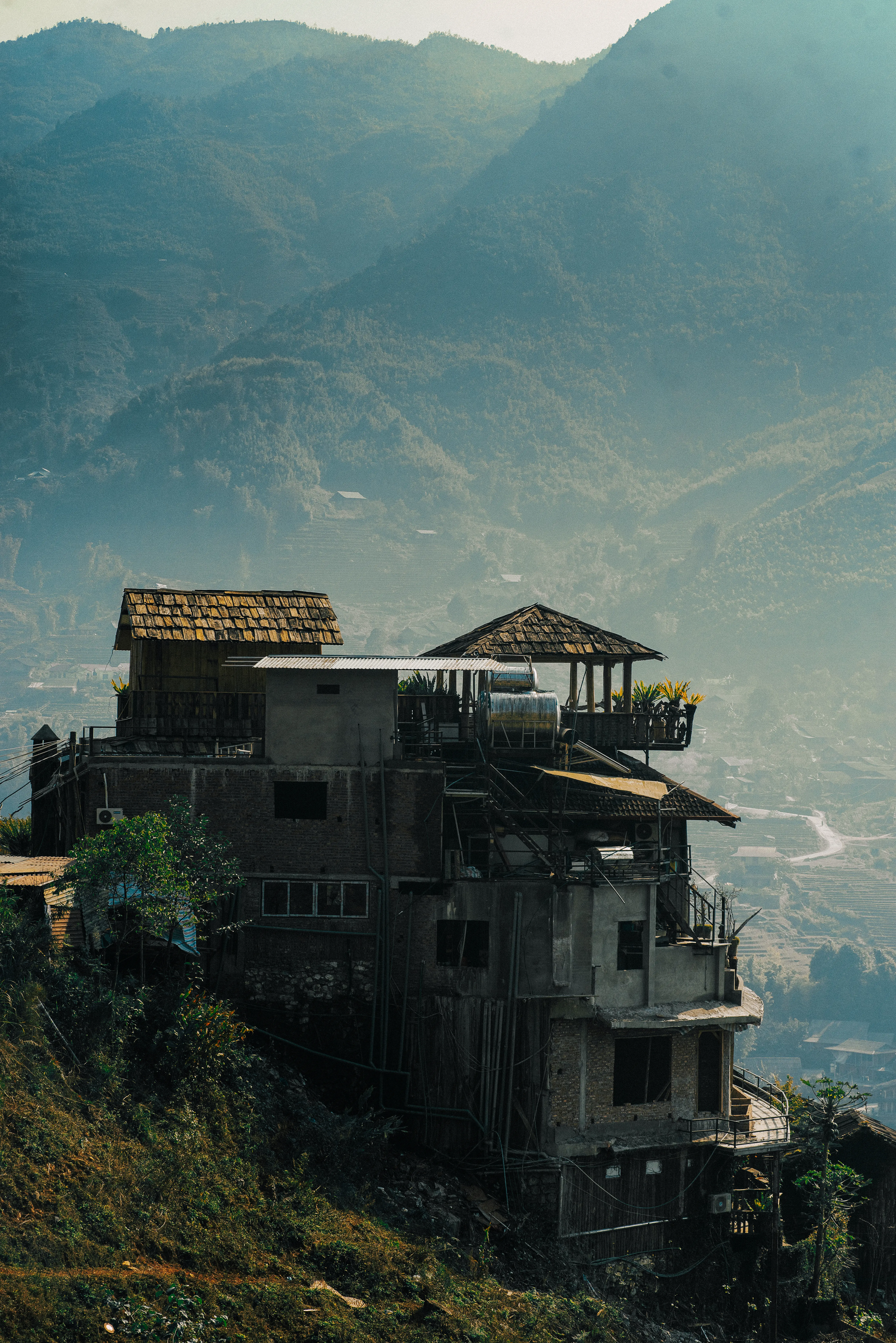 Multi-storey village house built into a steep hillside above terraced valleys in the hazy mountains of Sapa, Vietnam
