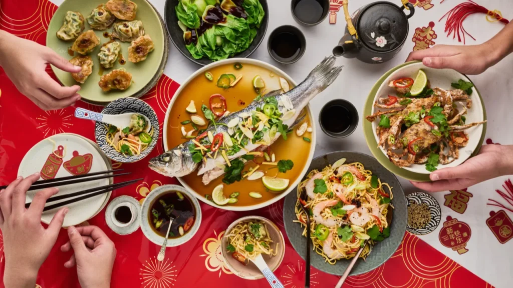 A photograph of a dinner spread with a whole fish as a centerpiece by Anusha Stewart.
