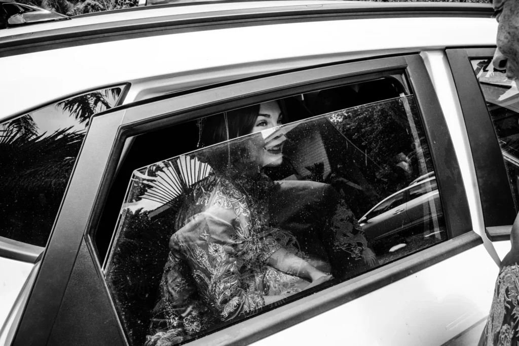 A photo of a woman peeking through a lowered car window by Antoine Didienne.